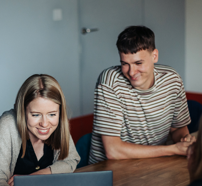 Women and men working together on a project, they are both smiling